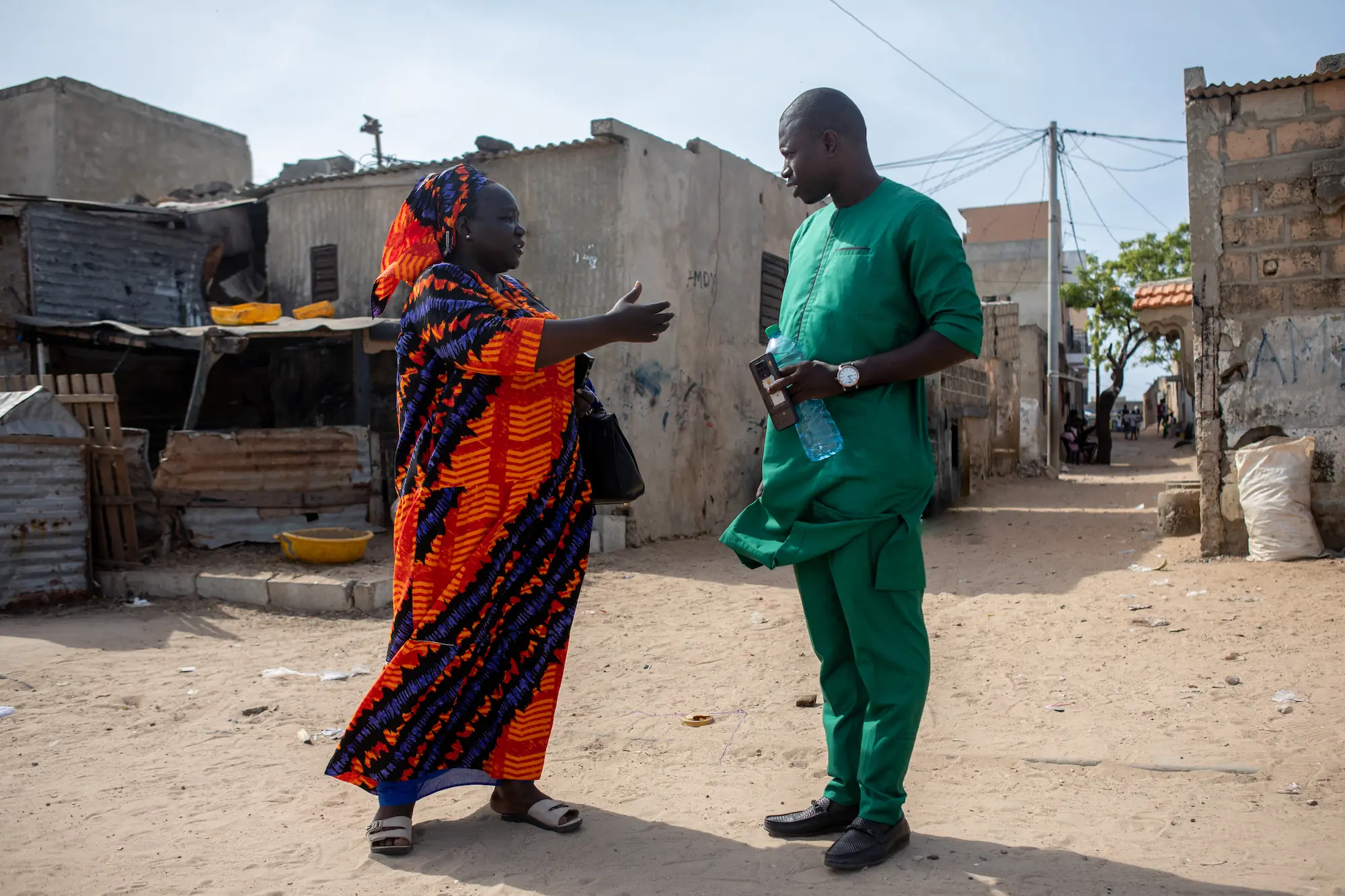 Astou Mbengue (L), lead data collector for the Senegalese Federation of Inhabitants, speaks with a government representative (R) during a site inspection in Pikine, Dakar