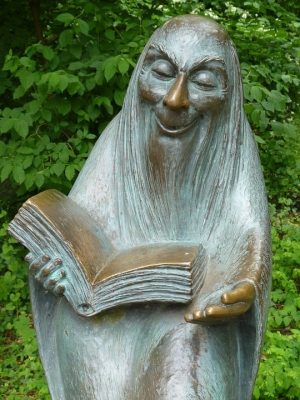 statue of person reading out of a book